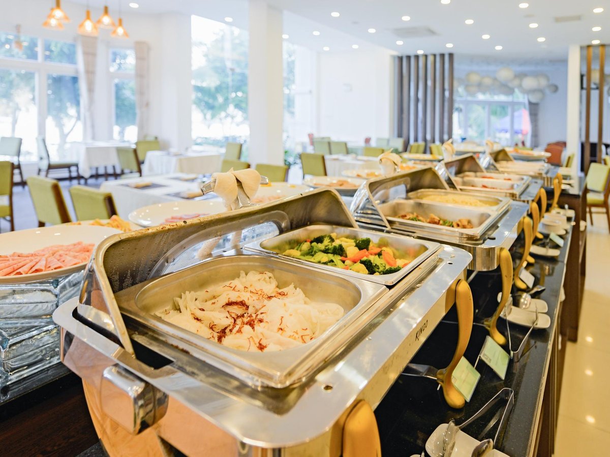 Breakfast buffet counter with chafing dishes in a bright restaurant with tiled floors
