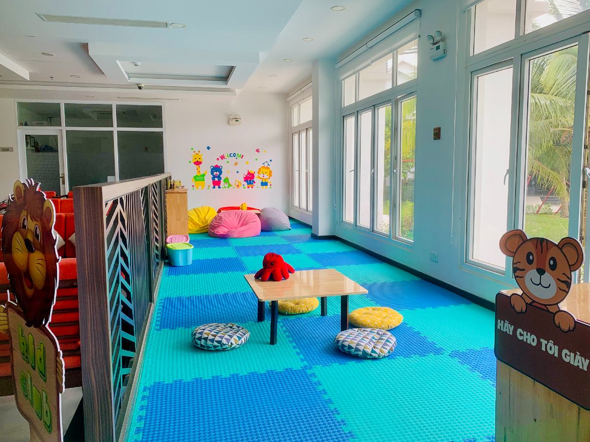 Bright indoor play room with soft coloured floor mats, low tables and bean bags
