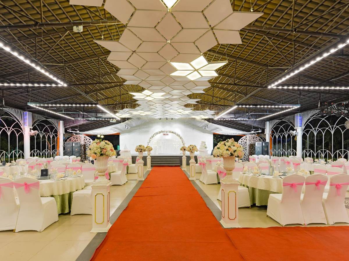 Grande salle de banquet avec chaises blanches, tables rondes et tapis rouge sous un plafond décoré