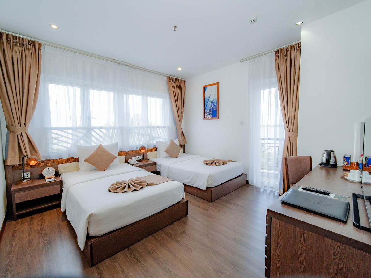 Großes Zimmer mit Doppelbett und zwei Einzelbetten auf Holzboden, mit Schreibtisch und Fenster