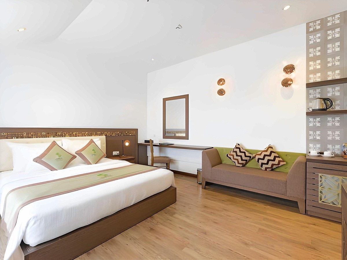 Double bed, a sofa and a patterned tile partition in a bright suite with a wooden floor