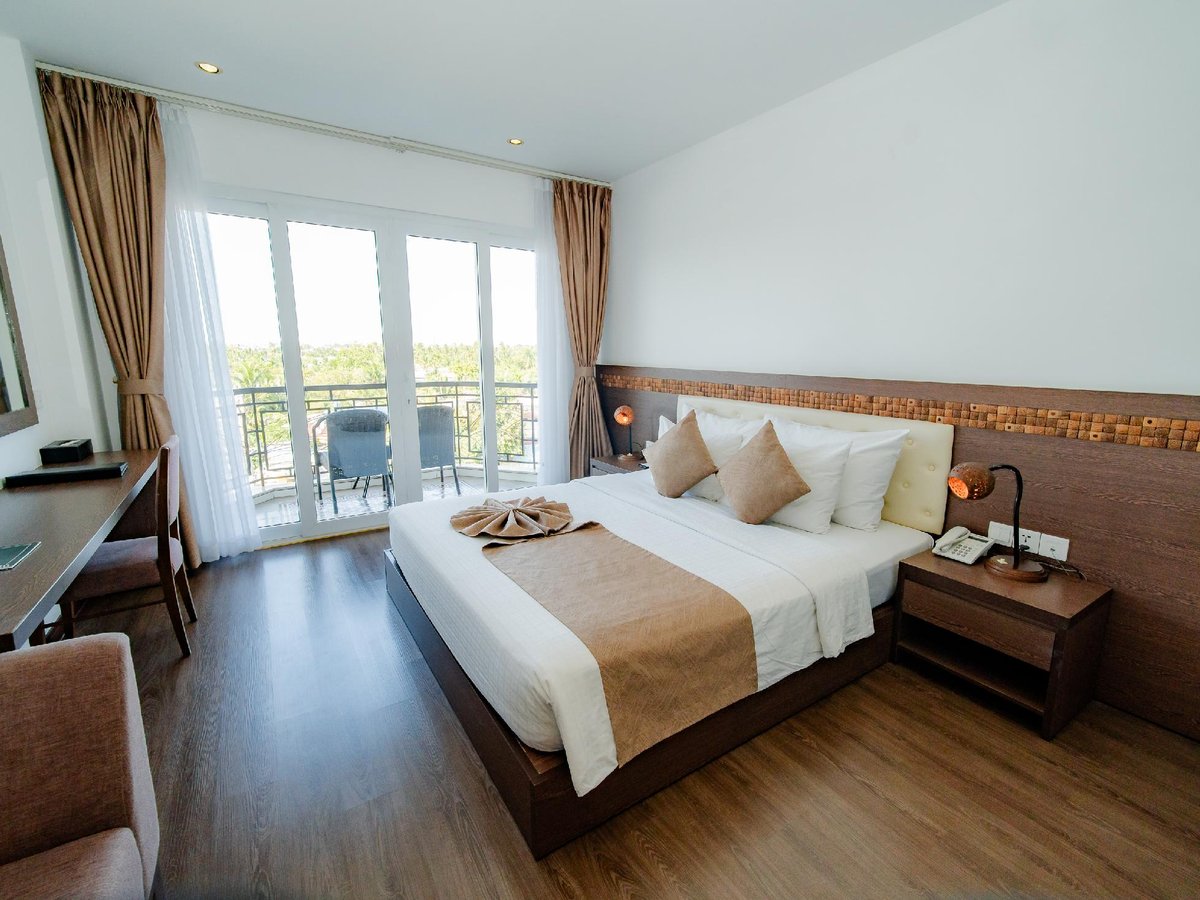 Double bed with a cream and green runner, a wooden floor and doors to a small balcony