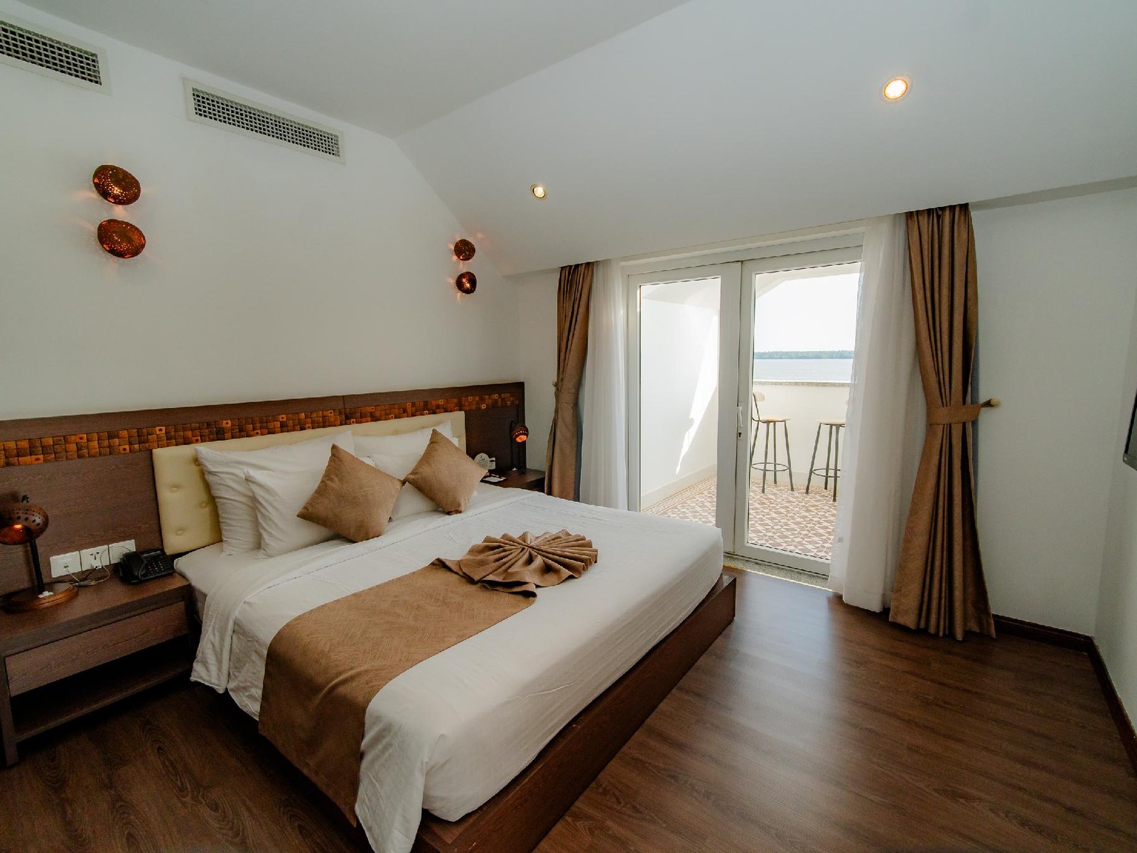 Hotel bedroom with a wooden floor, a double bed and glass doors opening onto a balcony