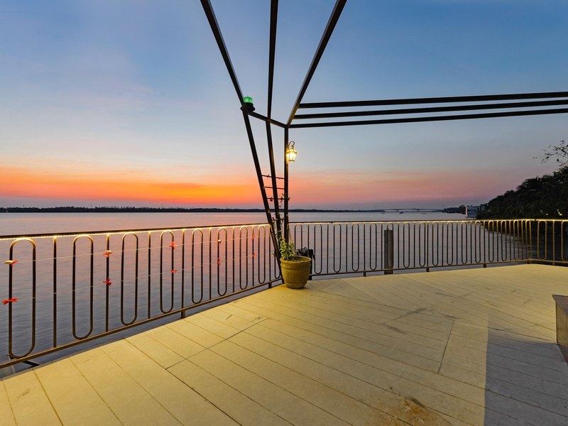 Holzdeck auf dem Dach mit dunklem Geländer über einem breiten Fluss bei Sonnenuntergang